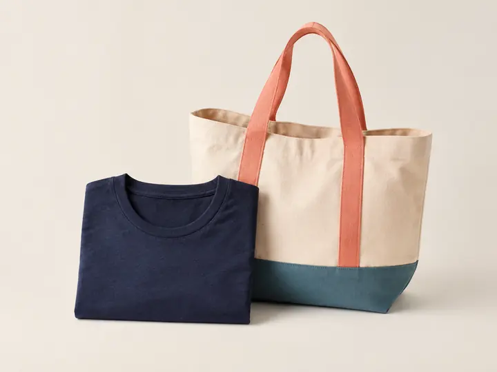 Folded navy T-shirt beside a canvas tote bag